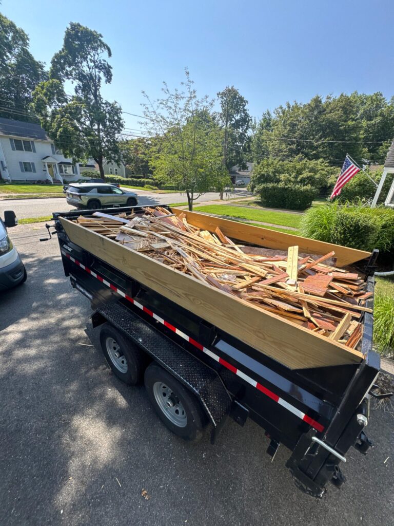 A professional dump trailer filled with old hardwood flooring debris following a removal project by Precision Hardwood Flooring at a residence in Bergen County, NJ.