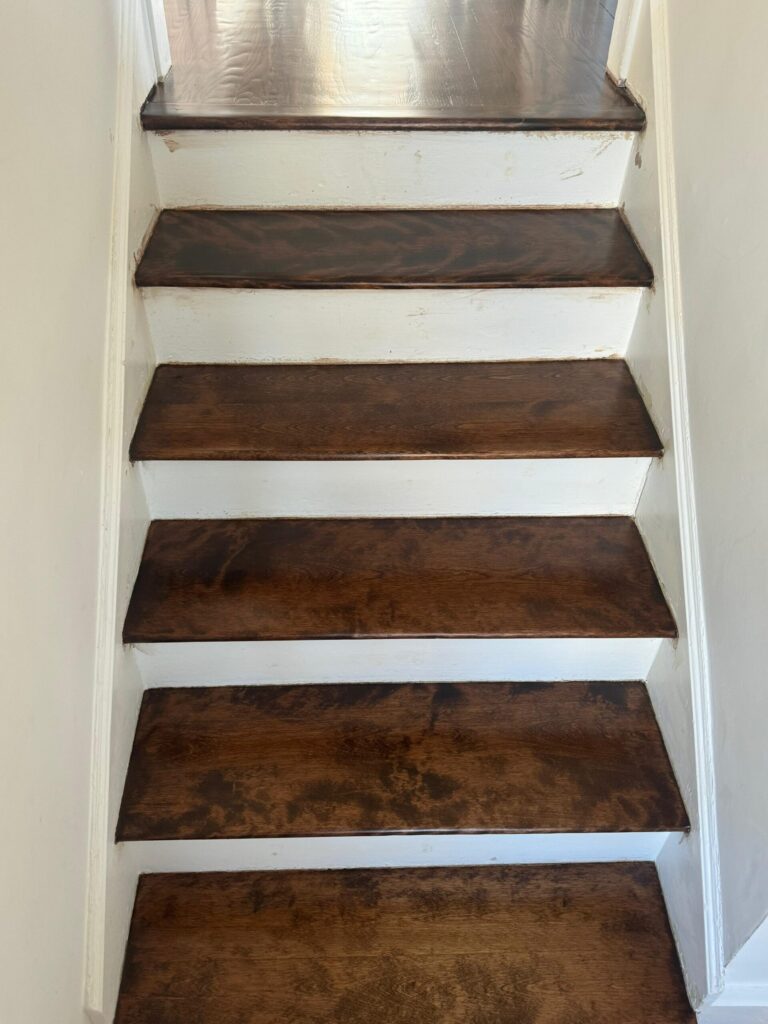 Close-up of a hardwood staircase refinished by Precision Hardwood Flooring in Bergen County, NJ, featuring deep mahogany-stained wood treads and fresh white-painted risers.