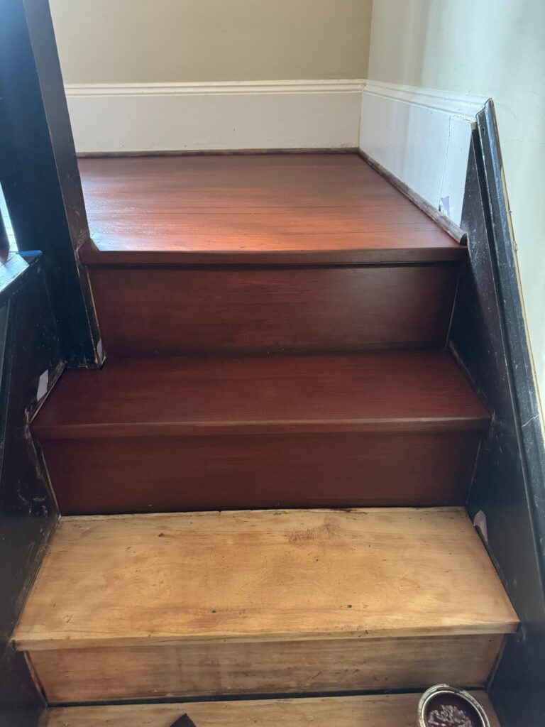 Top-down view of a professional hardwood staircase and hallway landing refinished with a deep walnut stain by Precision Hardwood Flooring in Bergen County, NJ.