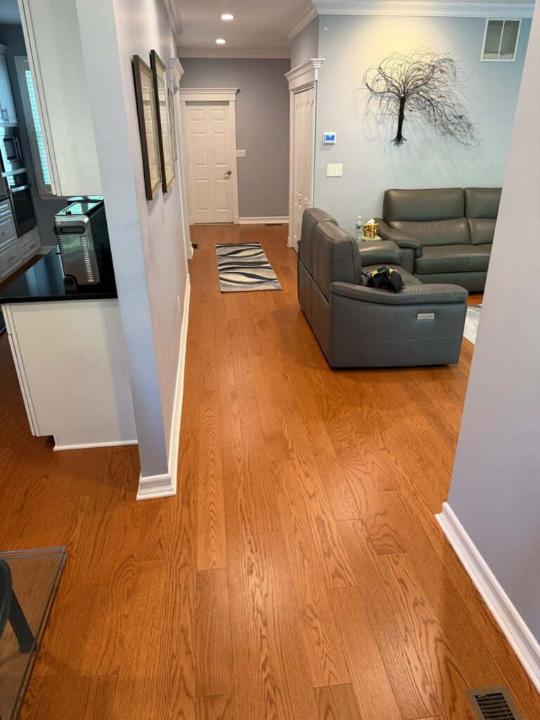 Natural hardwood floor refinishing through an open kitchen and living area